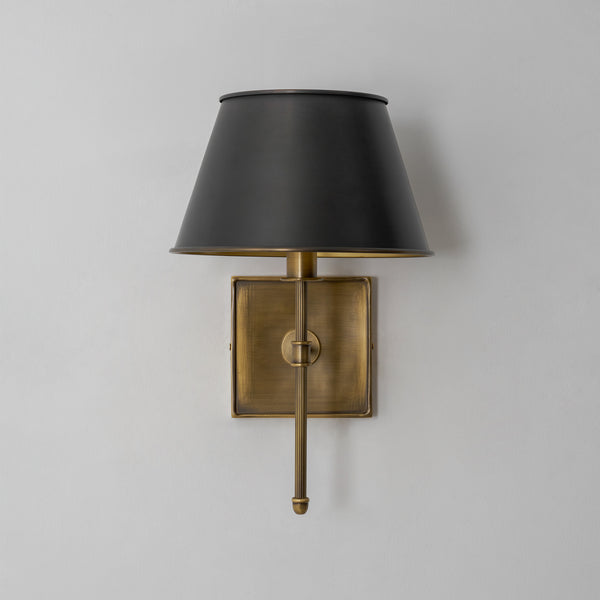 Rhodes wall sconce switched off, showing the matte black shade and antique brass backplate