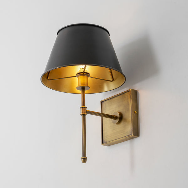 Rhodes Fluted Rod Wall Sconce in antique brass with a matte black shade and gold-toned interior, mounted on a white wall