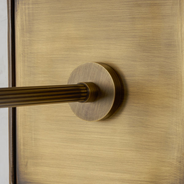 Close-up of the fluted brass arm meeting the brushed antique brass backplate